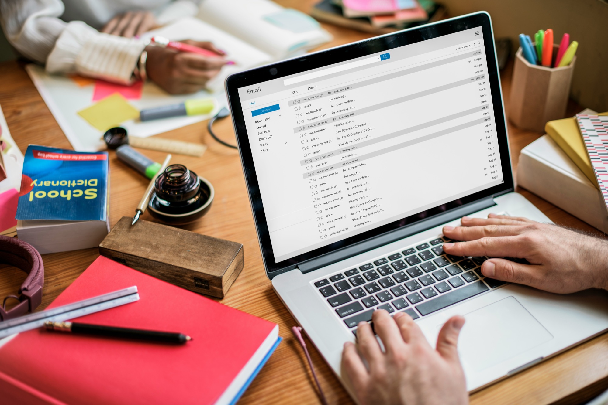 People using a laptop and stationery to organise and track business listing details