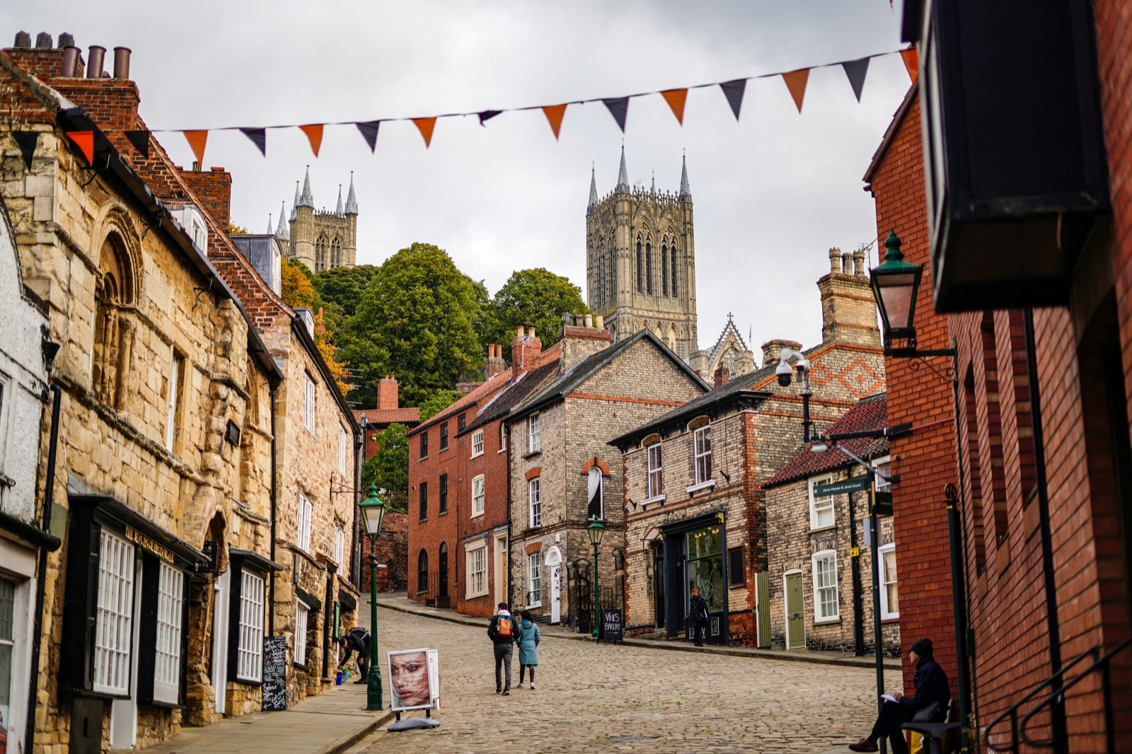 A cobbled street in Lincoln with Lincoln Cathedral visible behind local shops