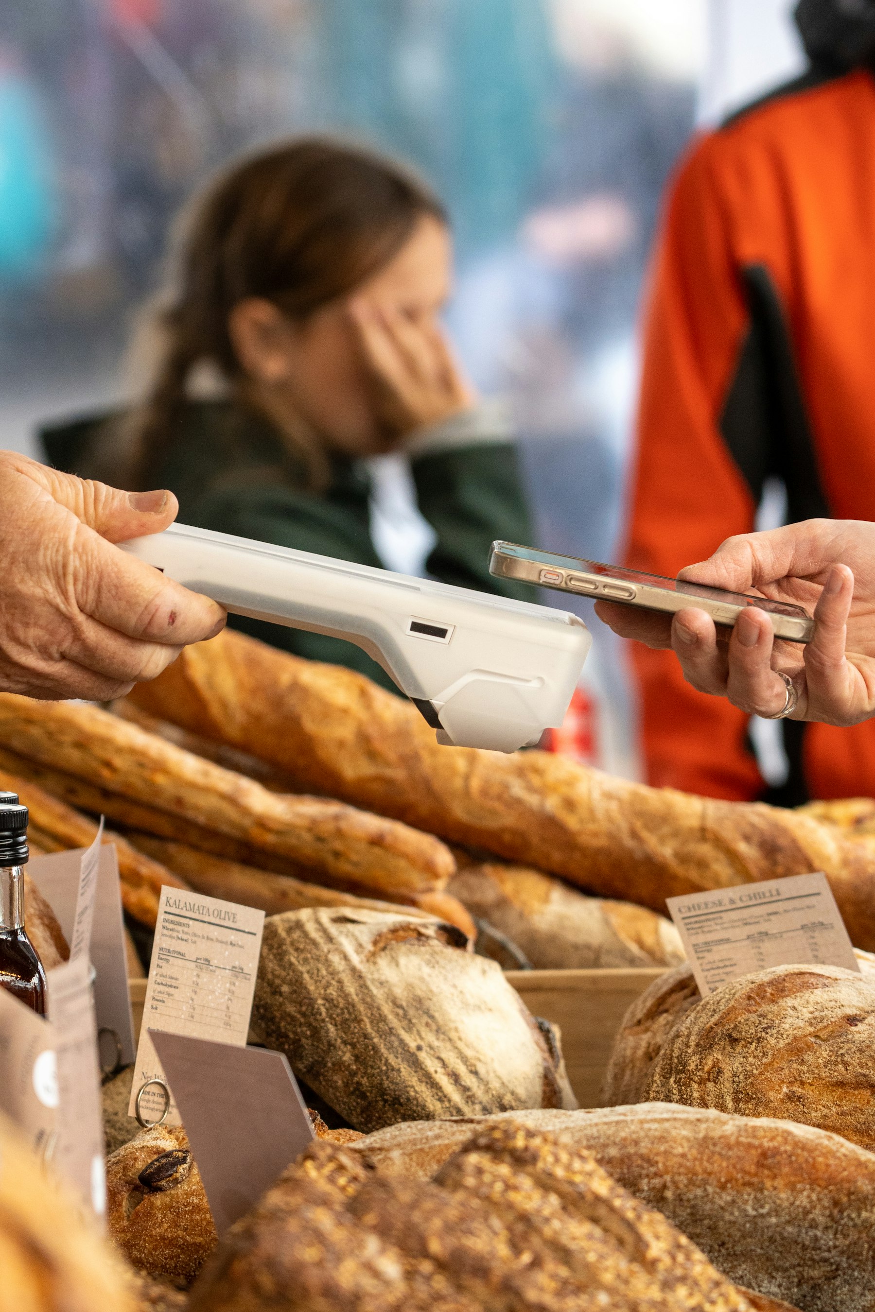 A customer paying by phone at a bakery market stall