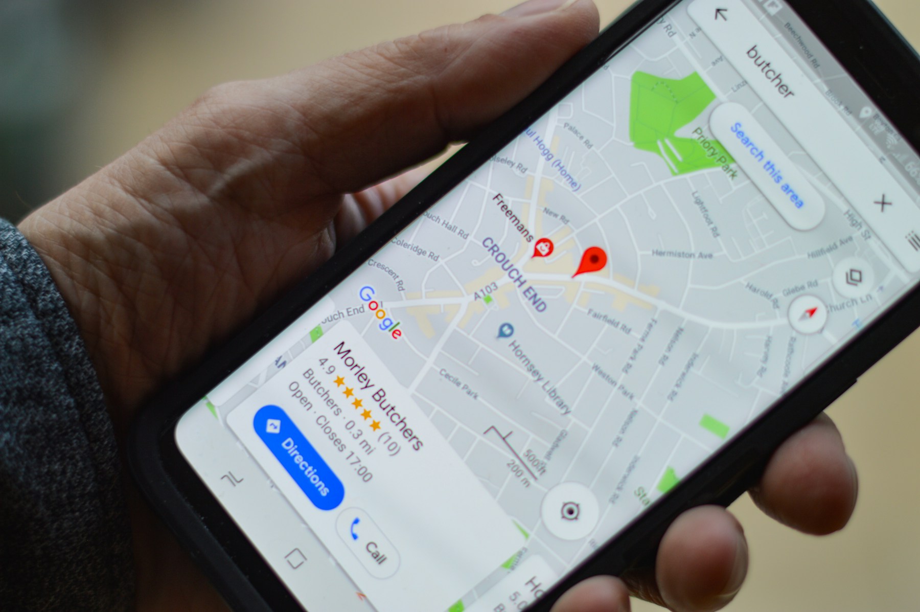Person using a smartphone to view a local business listing in Google Maps