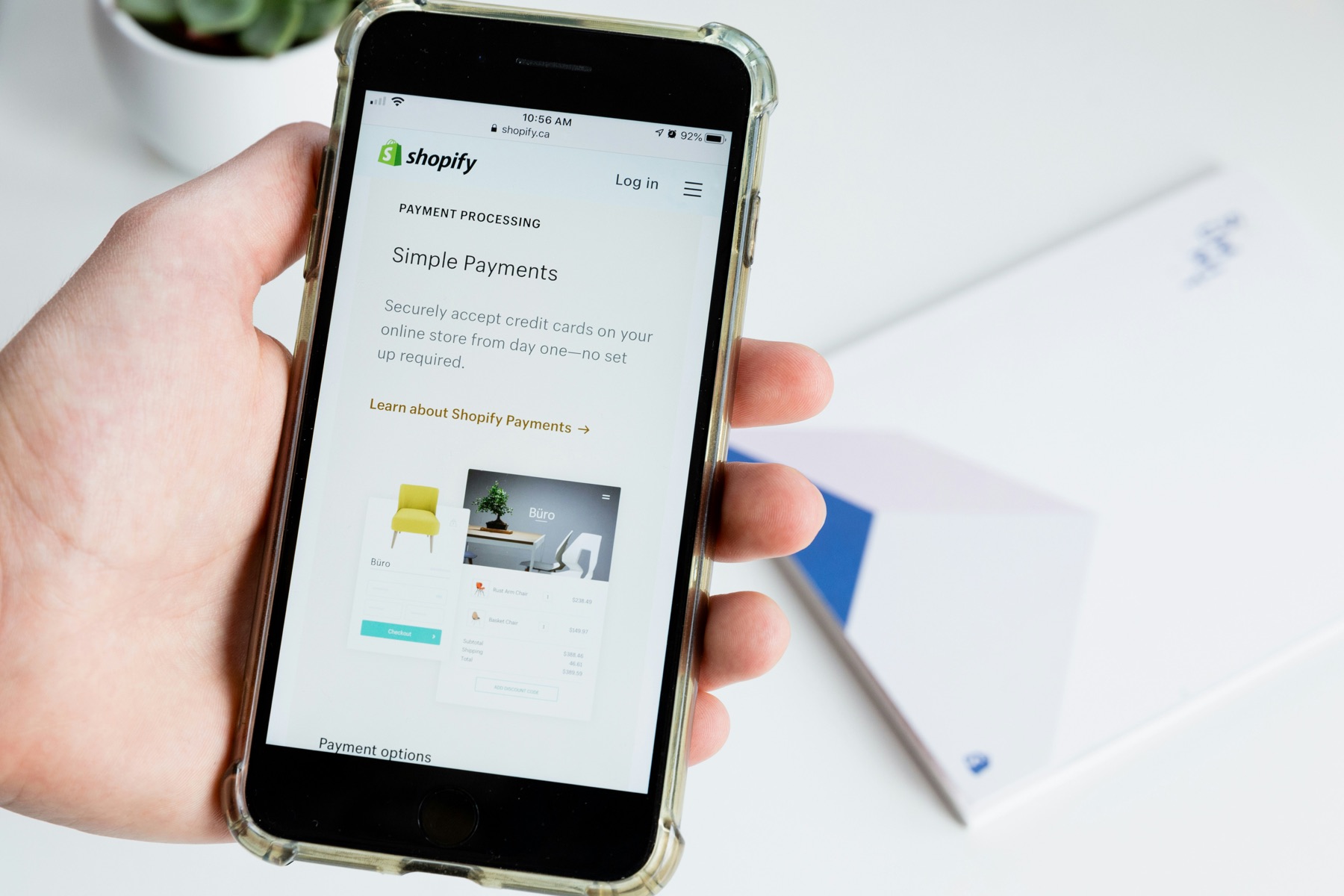A person holding a mobile phone displaying Shopify payment processing information