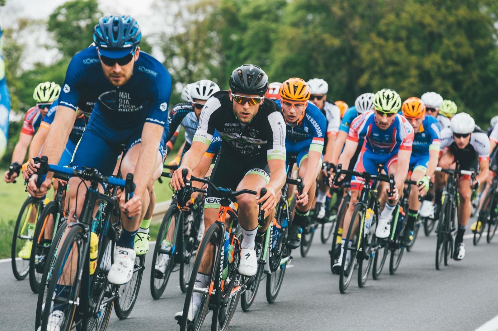 A group of road cyclists racing closely together during a cycling event