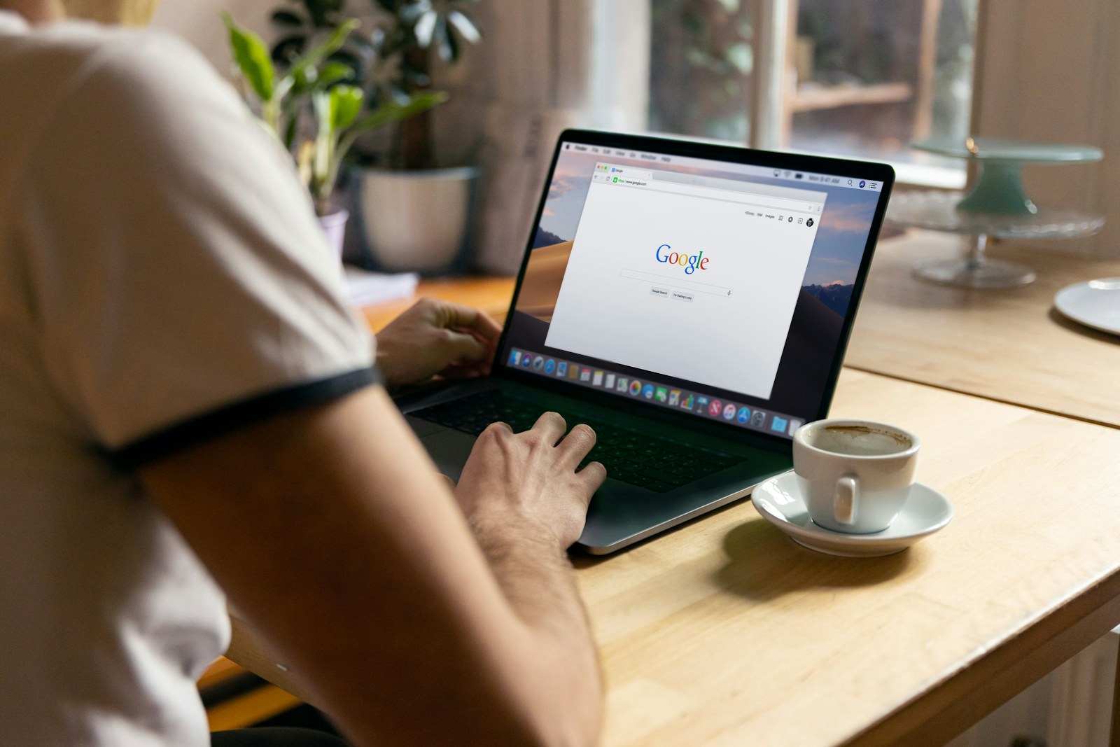 A person using Google Search on a laptop at a cafe table