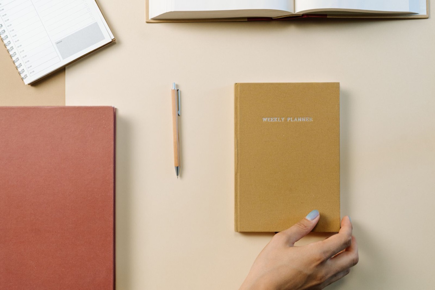 A weekly planner and notebooks arranged on a desk